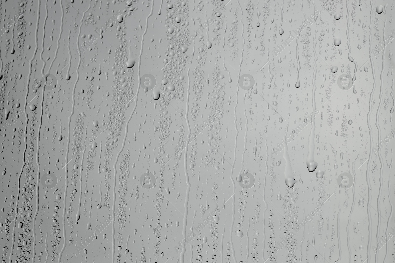 Photo of Water drops on grey glass surface, top view