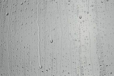 Photo of Water drops on grey glass surface, top view