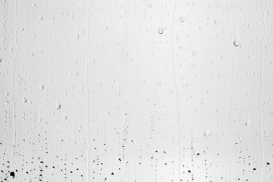 Photo of Water drops on light grey glass surface, top view