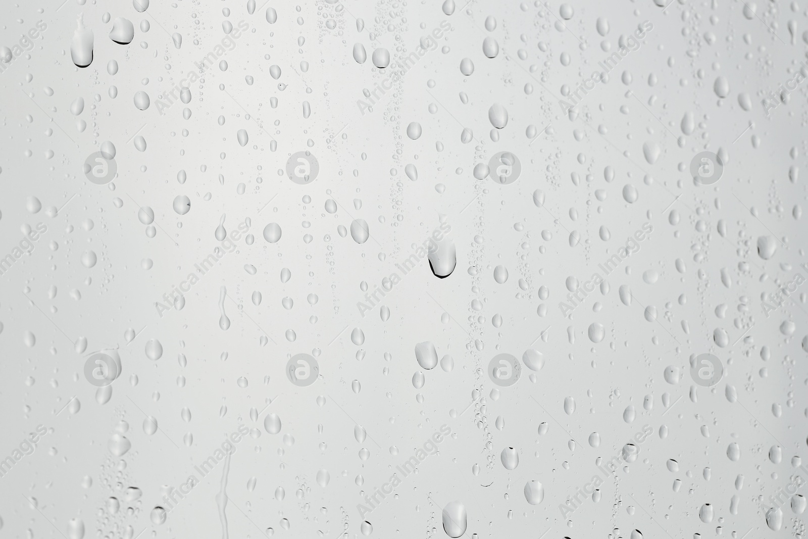 Photo of Water drops on light grey glass surface, closeup