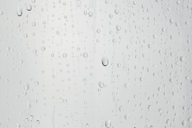 Water drops on light grey glass surface, closeup