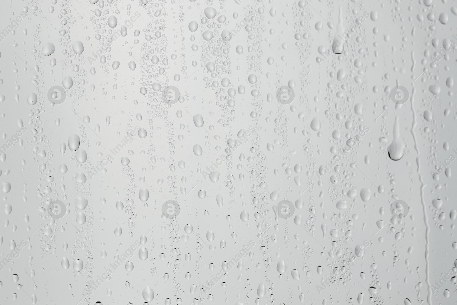 Photo of Water drops on light grey glass surface, closeup