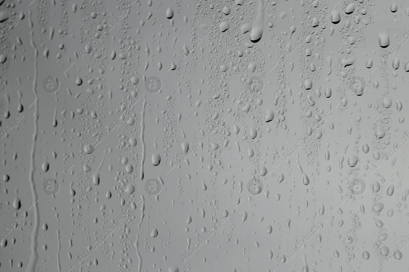 Photo of Water drops on grey glass surface, closeup