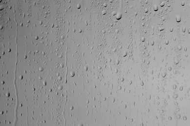 Photo of Water drops on grey glass surface, closeup