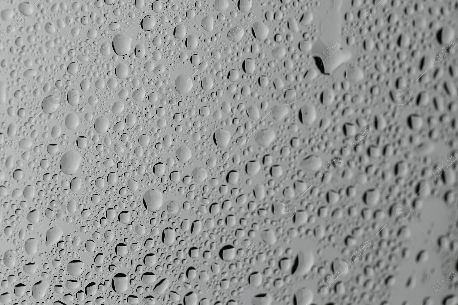 Photo of Water drops on grey glass surface, closeup