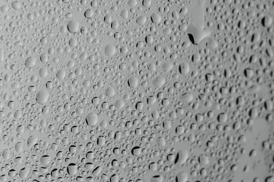 Photo of Water drops on grey glass surface, closeup