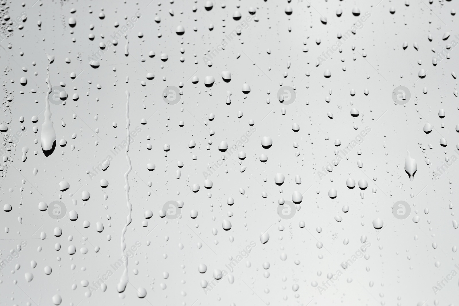 Photo of Water drops on light grey glass surface, closeup