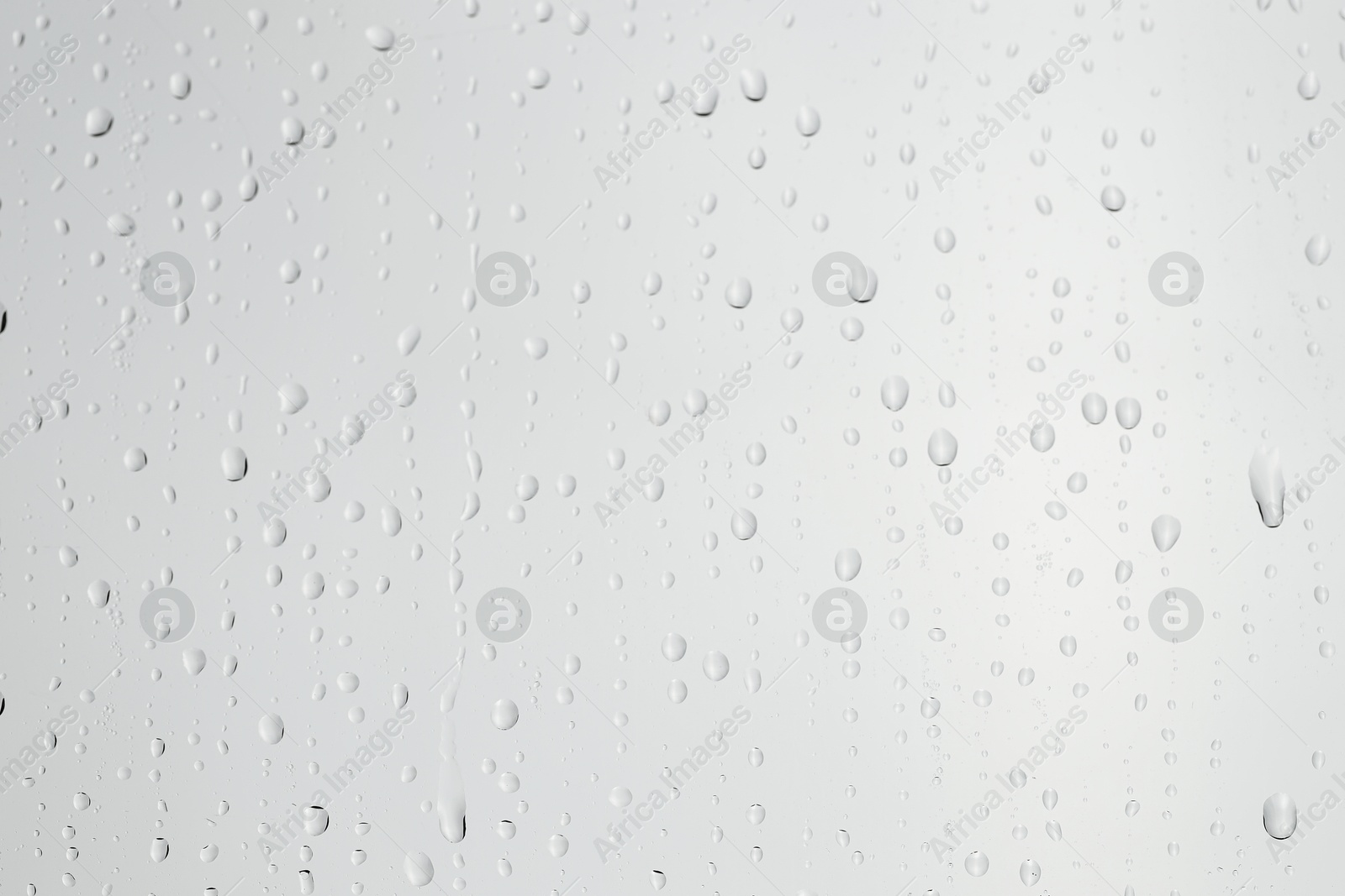 Photo of Water drops on light grey glass surface, closeup