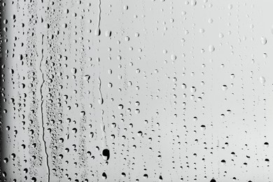 Photo of Water drops on light grey glass surface, top view