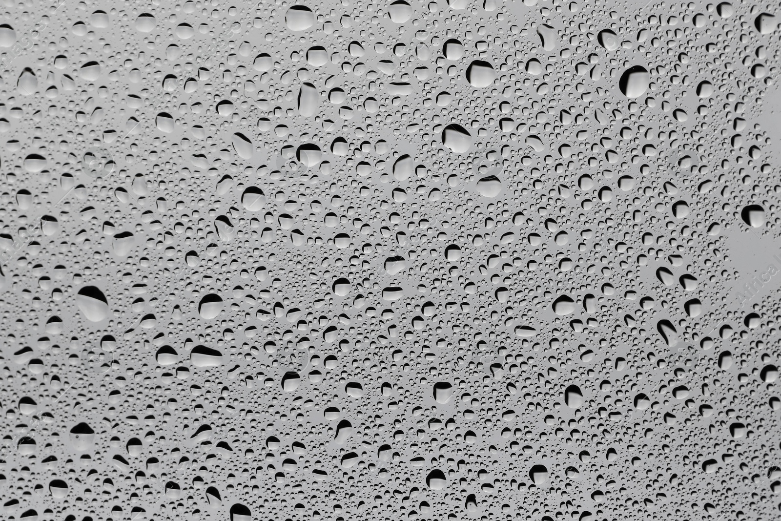 Photo of Water drops on grey glass surface, top view