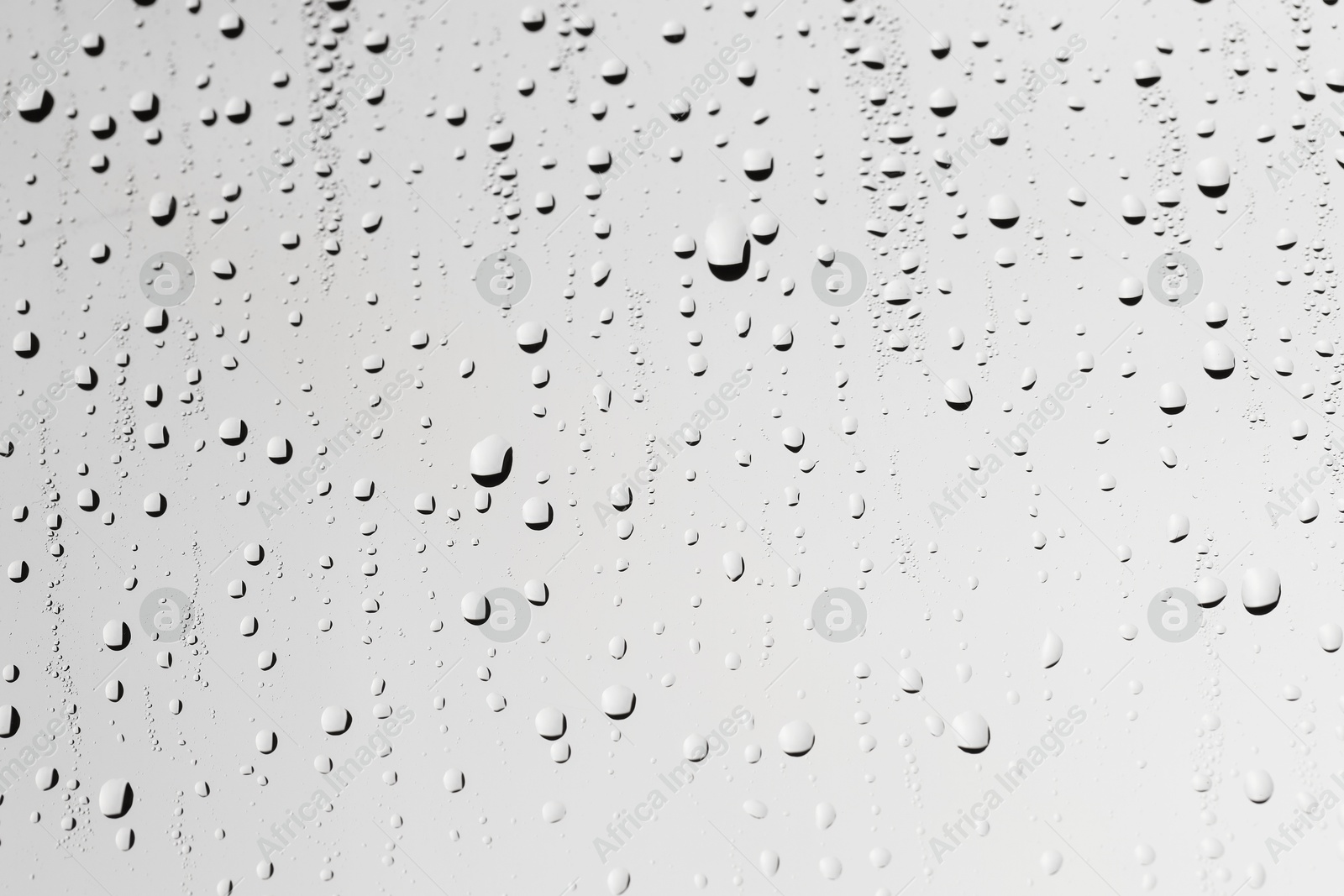 Photo of Water drops on light grey glass surface, closeup