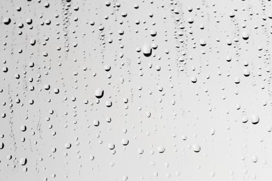 Water drops on light grey glass surface, closeup