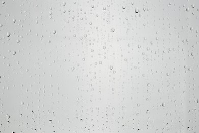 Water drops on light grey glass surface, top view