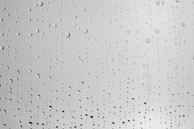 Photo of Water drops on light grey glass surface, top view