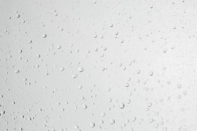 Photo of Water drops on light grey glass surface, top view