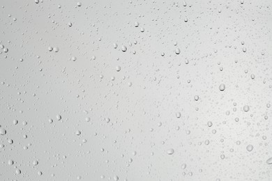 Water drops on light grey glass surface, top view