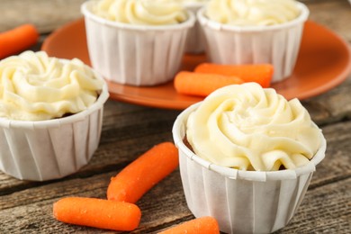 Photo of Delicious carrot muffins and fresh vegetables on wooden table, closeup