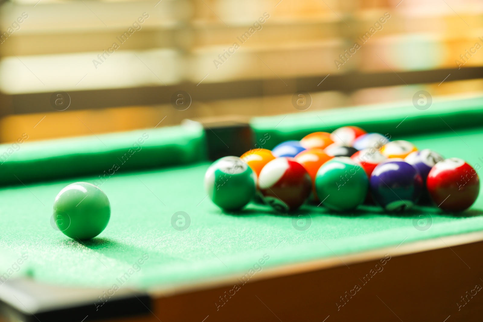 Photo of Billiard balls in triangle on green table indoors, closeup. Space for text