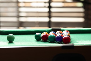 Photo of Billiard balls in triangle on green table indoors. Space for text