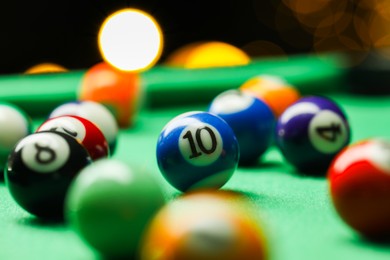 Photo of Many colorful billiard balls on green table indoors, closeup