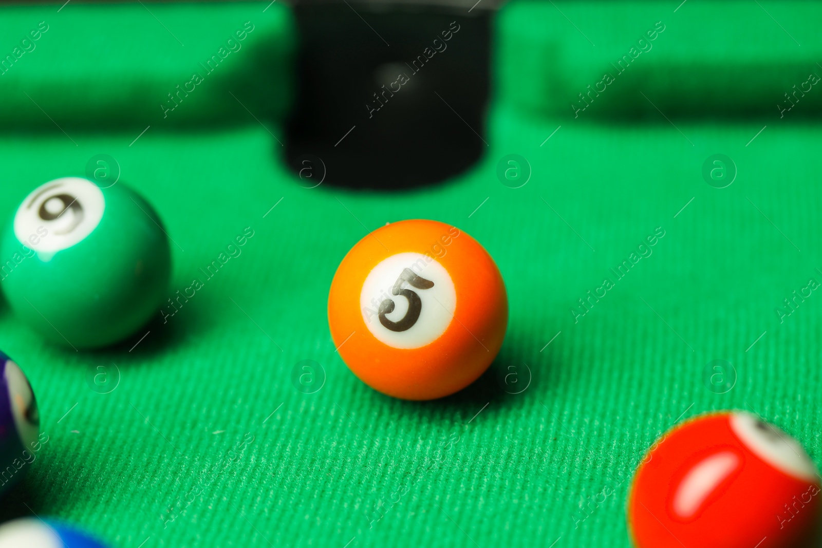 Photo of Many colorful billiard balls on green table, closeup