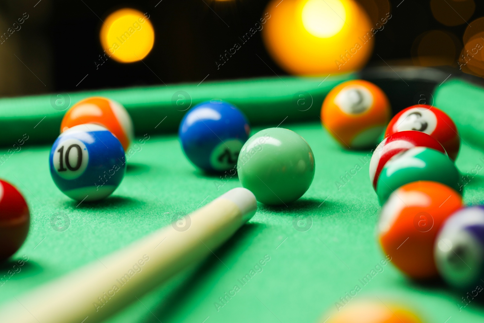 Photo of Many colorful billiard balls and cue on green table indoors, closeup