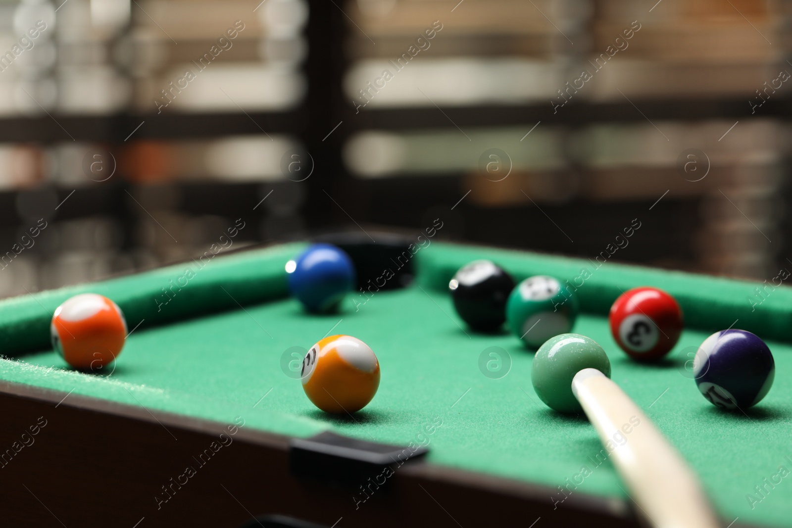 Photo of Many colorful billiard balls and cue on green table indoors, closeup. Space for text