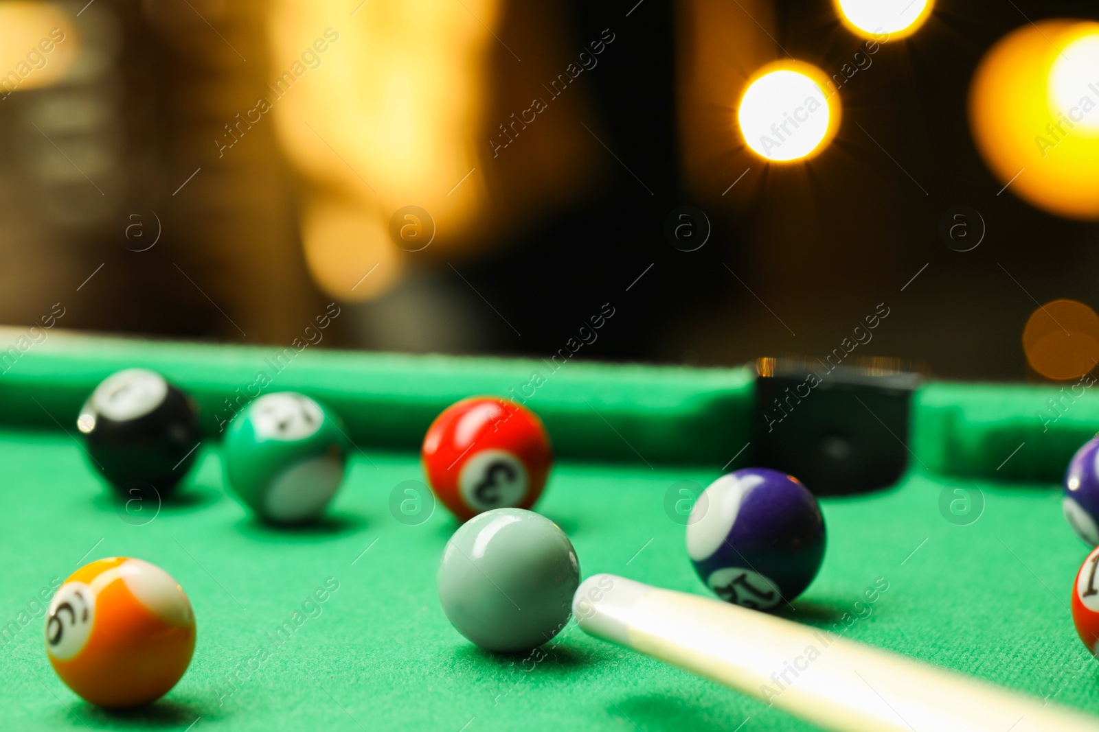 Photo of Many colorful billiard balls and cue on green table indoors, closeup. Space for text