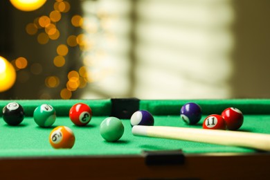 Photo of Many colorful billiard balls and cue on green table indoors, closeup. Space for text