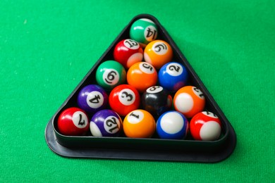 Photo of Billiard balls triangle rack on green table, closeup