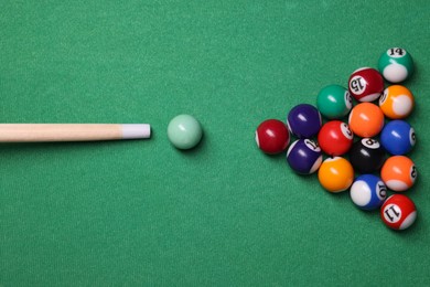 Photo of Billiard balls in triangle and cue on green table, top view