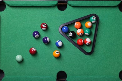 Photo of Billiard balls and rack on green table, flat lay