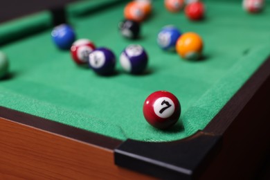 Photo of Many colorful billiard balls on green table, closeup