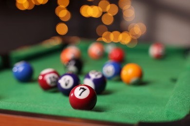 Photo of Many colorful billiard balls on green table indoors, closeup