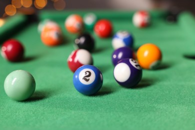 Photo of Many colorful billiard balls on green table indoors, closeup