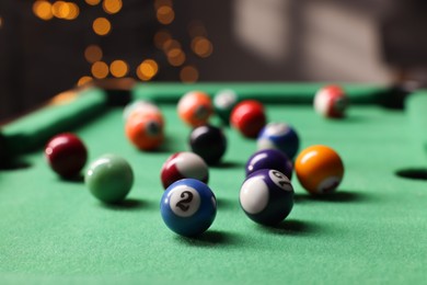 Photo of Many colorful billiard balls on green table indoors, closeup