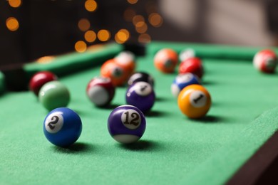 Photo of Many colorful billiard balls on green table indoors, closeup