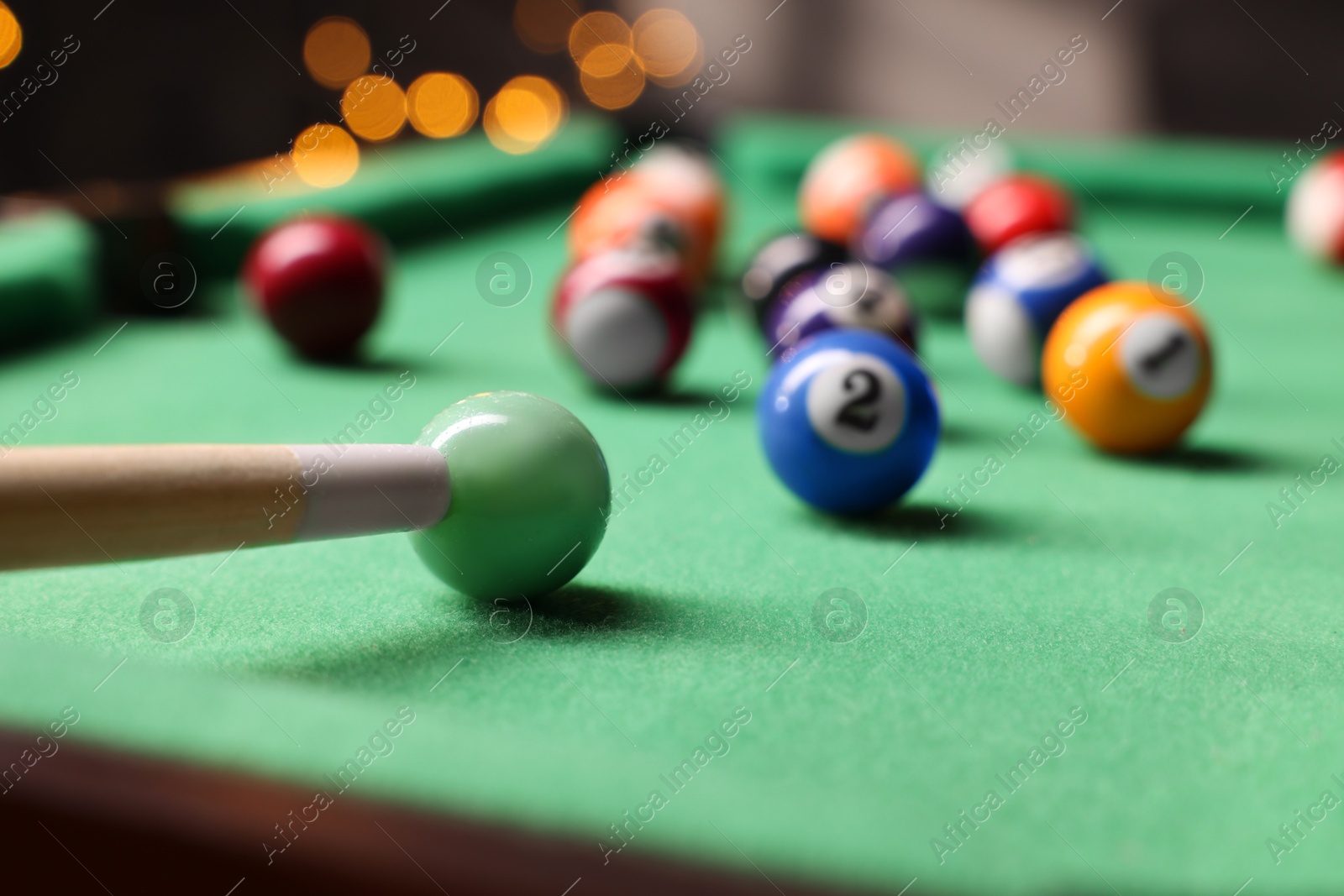 Photo of Many colorful billiard balls and cue on green table indoors, closeup