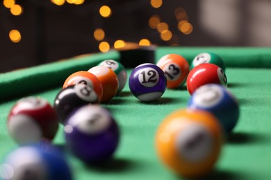 Photo of Many colorful billiard balls on green table indoors, closeup