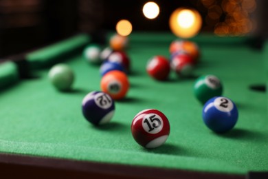 Photo of Many colorful billiard balls on green table indoors, closeup