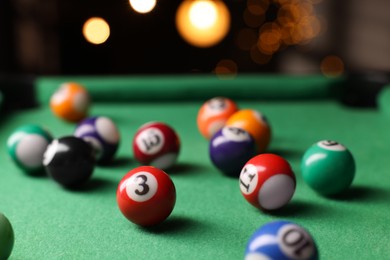 Photo of Many colorful billiard balls on green table indoors, closeup