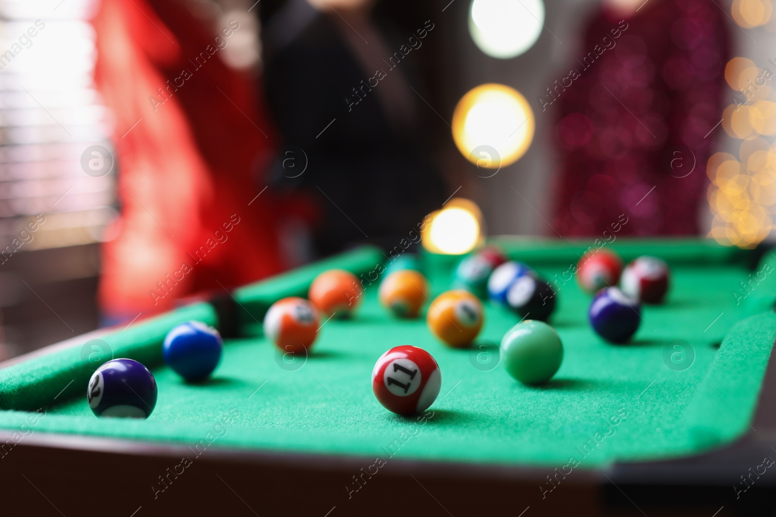 Photo of People near green billiard table with many colorful balls indoors, selective focus