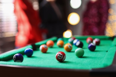 Photo of People near green billiard table with many colorful balls indoors, selective focus