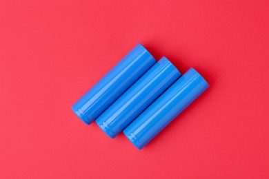 Photo of Three AA cell batteries on red background, top view