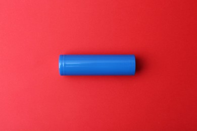 Photo of One AA cell battery on red background, top view