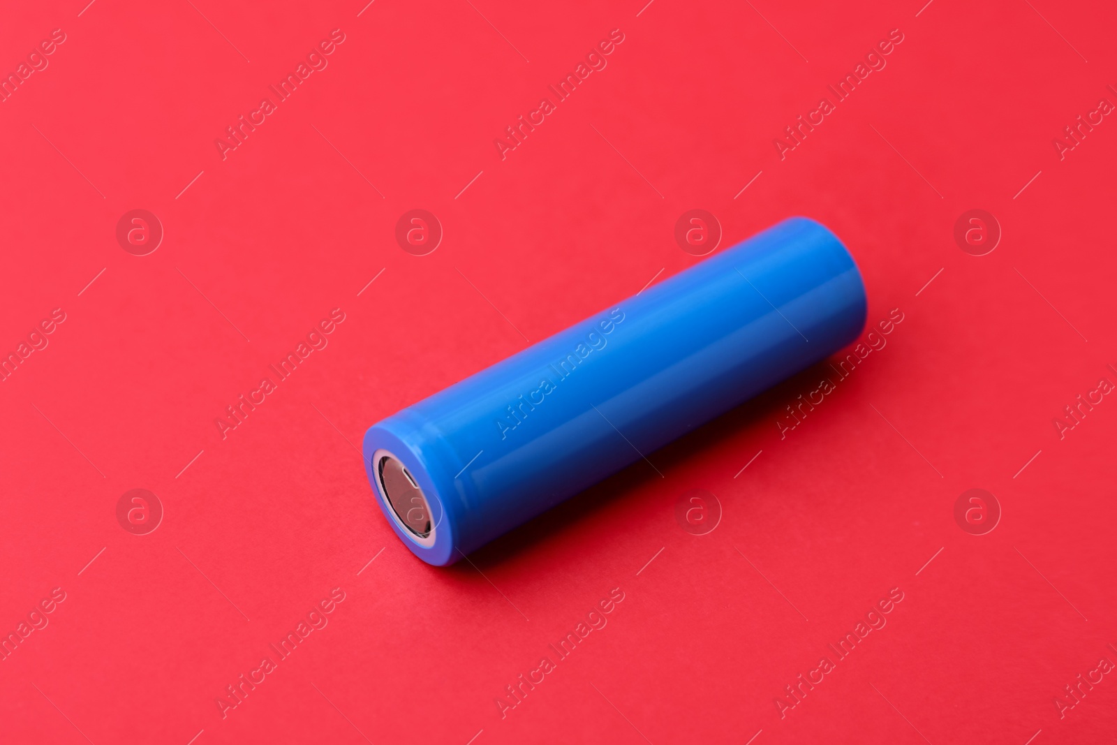 Photo of One AA cell battery on red background, closeup. Space for text