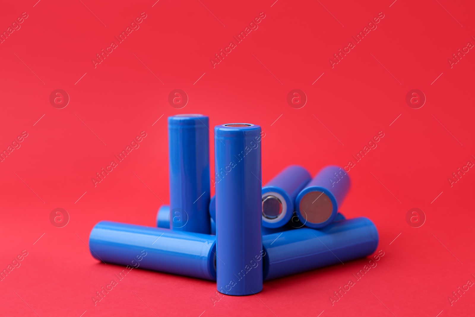 Photo of Many AA cell batteries on red background, closeup