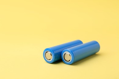 Photo of Two AA cell batteries on yellow background, closeup. Space for text