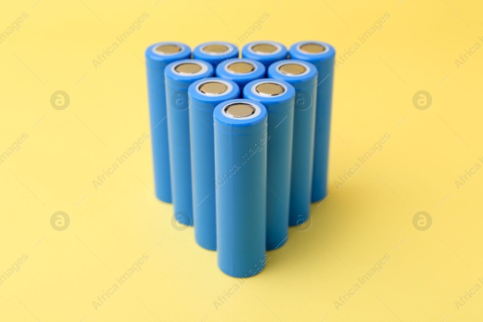 Photo of Many AA cell batteries on yellow background, closeup