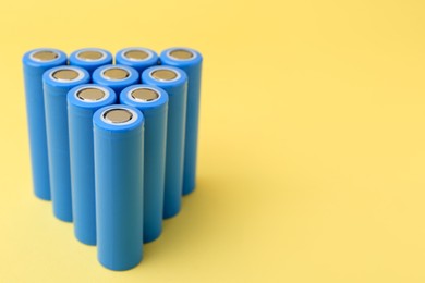 Photo of Many AA cell batteries on yellow background, closeup. Space for text